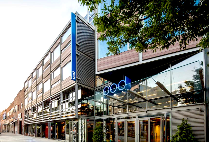 Exterior photo of Pod Hotel showing modular rooms and blue sign above street level, designed by Peter Dann Engineers