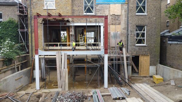 Construction of a two-storey extension at rear of large residential building with exposed steelwork.