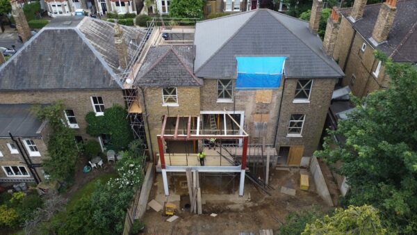 Aerial shot of residential building with construction of a two-storey extension at rear.