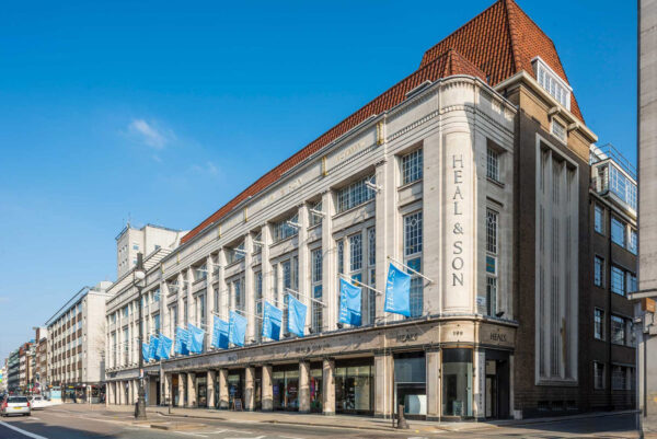 Heal's Building Department Store on Tottenham Court Road with blue flags flying and a blue sky