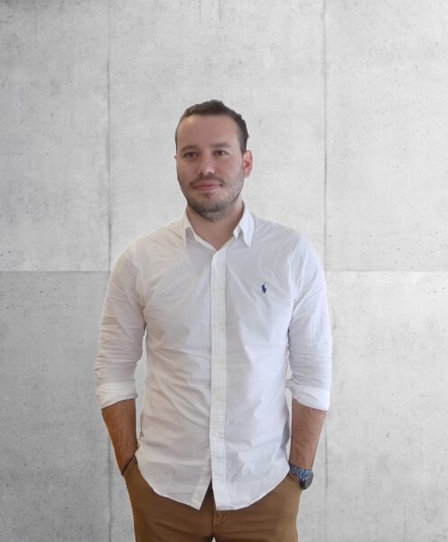 Project engineer in white shirt and camel chinos standing in front of a polished concrete wall