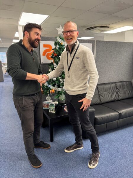 Two male structural engineers shaking hands in an office