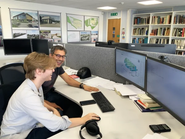 Summer engineering intern at desk with his mentor in an office
