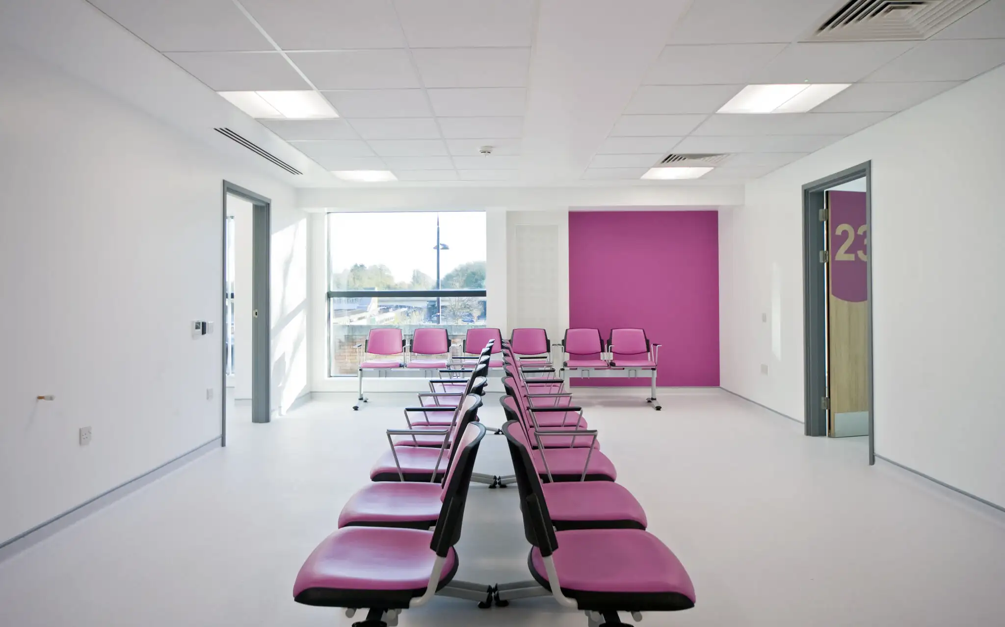 New white waiting room for bromley health and wellbeing centre with feature pink wall and chairs