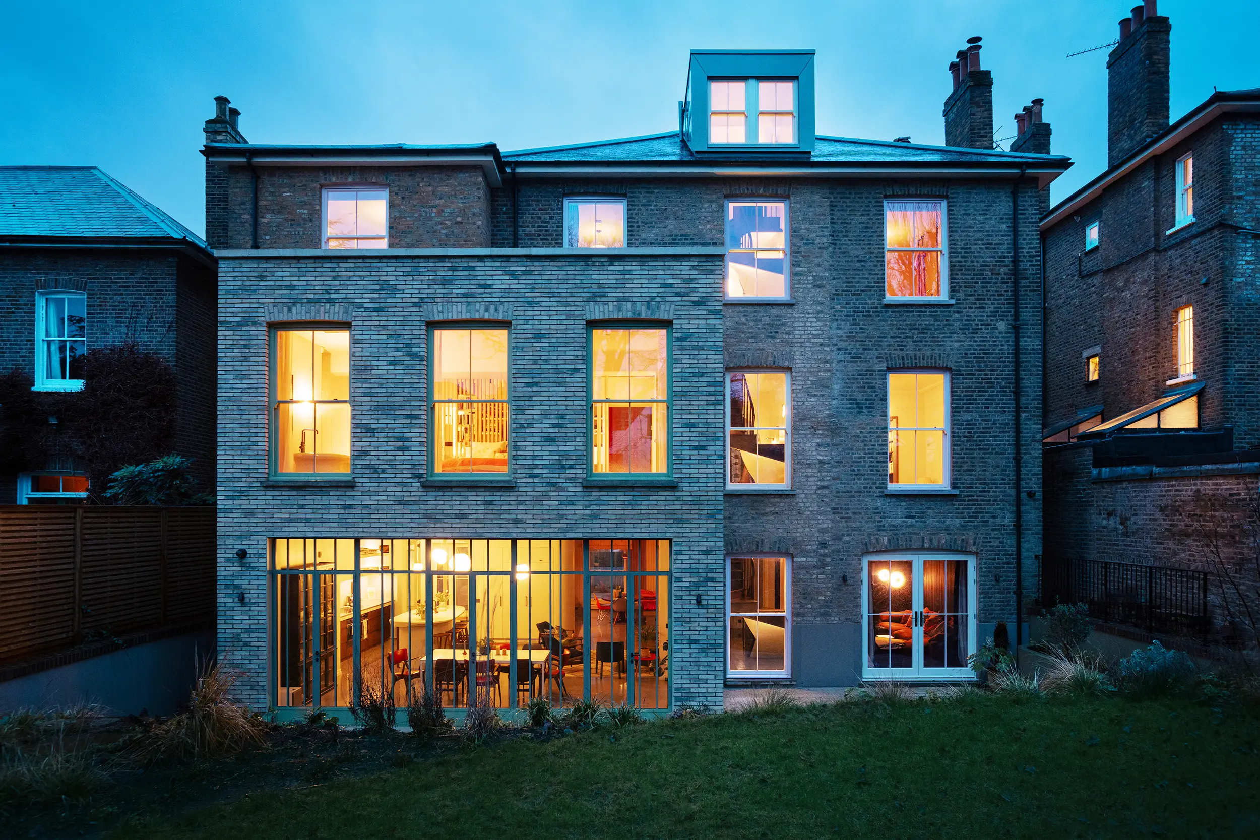 Exterior view of large property extension into garden at dusk